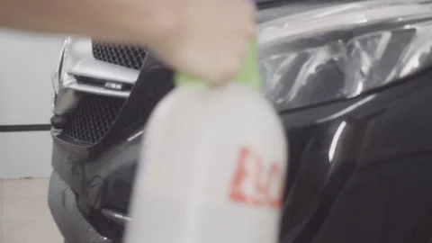 A man washes the front of the car before applying a protective layer on it Stock Footage 93603964