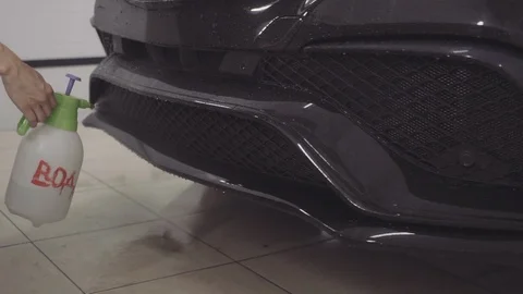 A man washes the front of the car before applying a protective layer on it Stock Footage 93604019