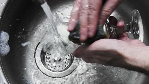 A man washes a glass goblet with a sponge. Home life. Slow motion video Stock Footage 153244227