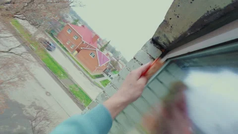 A man washes the glass of a plastic window outside the apartment with a sponge. Vidéo 334129799
