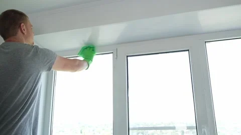A man washes glass window and a plastic frame with a folk remedy with household Stock Footage 201630043