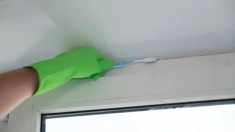 A man washes glass window and a plastic frame with a folk remedy with household Stock Footage 202046015