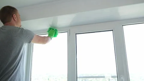 A man washes glass window and a plastic frame with a folk remedy with household Stock Footage 202046053