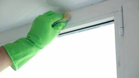 A man washes glass window and a plastic frame with a folk remedy with household Stock Footage 205941376