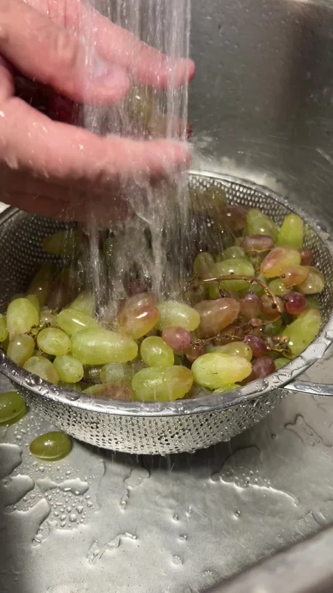 Man washes green grape in colander in metal sink in kitchen under faucet Stock Footage 293627017