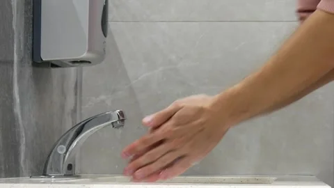 A man washes hands with a soap in a restroom and dries them with a hand dryer Vidéo 249954459