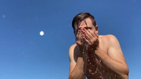 A man washes himself by the river, against the background of the sky Stock Footage 280759371