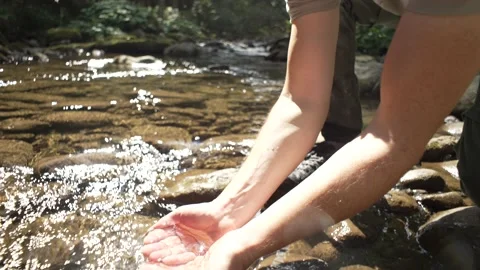 A man washes his face in the river while hiking in the mountains. Stock Footage 211815506