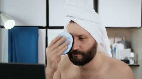 Man washes his face with sponge. Travesty, young attractive caucasian man looks Vídeos de archivo 128233826
