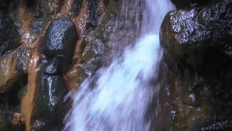 A man washes his face in a waterfall. A large stream of water falls on the man. Vídeos de archivo 133656883