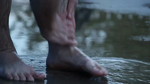 Man washes his feet in a puddle after the rain Stock Footage 107948040