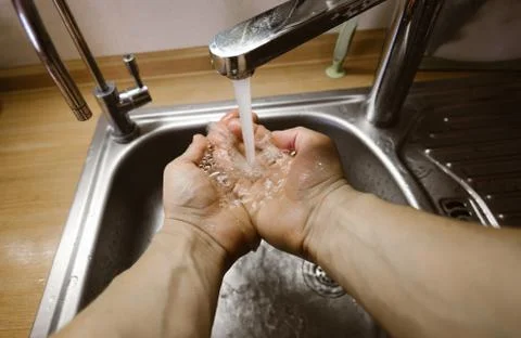 A man washes his hands in the kitchen in a steel sink. Wide angle first person Stock Photos