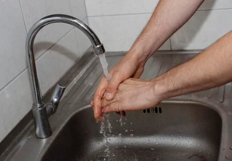 Man washes his hands in the kitchen under the tap close up Stock Photos