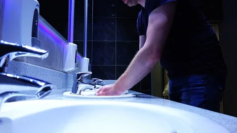 A man washes his hands with soap in the sink in the toilet Stock Footage 80240651