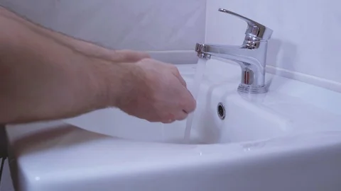A man washes his hands with soap in a gray bathroom Stock Footage 130010400
