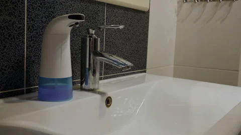 A man washes his hands with soap for disinfection. Water pours from the tap on Stock Footage 137173067