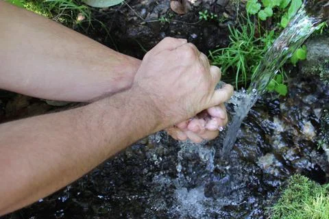 A man washes his hands at a spring in the forest. Blurred back natural Stock Photos