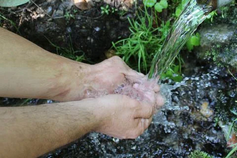 A man washes his hands at a spring in the forest. Blurred back natural Stock Photos