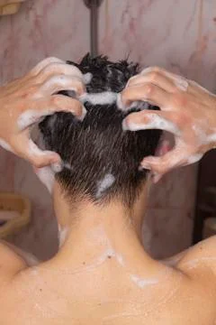 A man washes his head. Foamy short black hair. Shower, rear view. Daily. Stock Photos