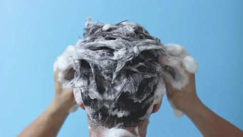 A man washes his head with shampoo on blue background, rear view Stock Footage 137482712