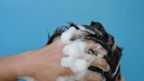 Man washes his head with shampoo on blue background close-up, back view. Vidéo 163725312