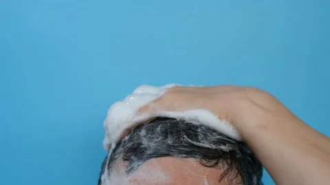 A man washes his head with shampoo on blue background close-up. Stock Footage 163889088