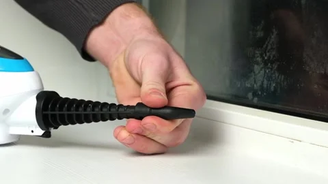 A man washes the joints on window with a steam cleaner. Steam cleaner for Stock Footage 171226784