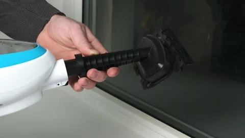 A man washes the joints on window with a steam cleaner. Steam cleaner for Stock Footage 171595886
