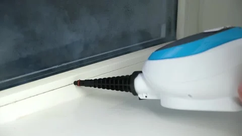 A man washes the joints on window with a steam cleaner. Steam cleaner for Stock Footage 171833080