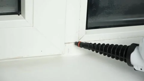 A man washes the joints on window with a steam cleaner. Steam cleaner for Видео 182593172