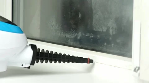 A man washes the joints on window with a steam cleaner. Steam cleaner for Video stock 185705621