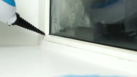 A man washes the joints on window with a steam cleaner. Steam cleaner for Stock-Footage 188576708
