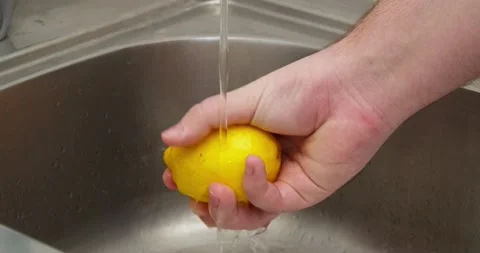 A man washes a lemon Stock Footage 235512343