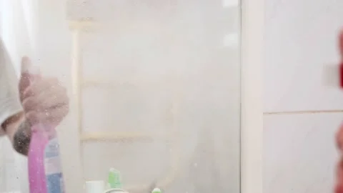 The man washes the mirror in the white bathroom Stock Footage 156030830