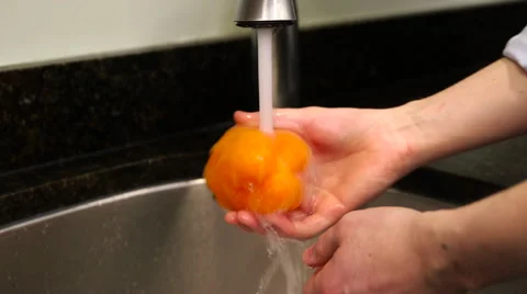 Man washes orange bell pepper in sink Stock Footage 61393649
