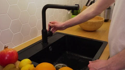A man washes the oranges under running water Stock Footage 129054508