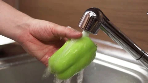 A man washes an pepper under running water from a tap. 스톡 동영상 160615611