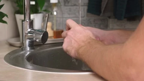 A man washes a potato from ground under a stream of tap water for further Stock Footage 230721269