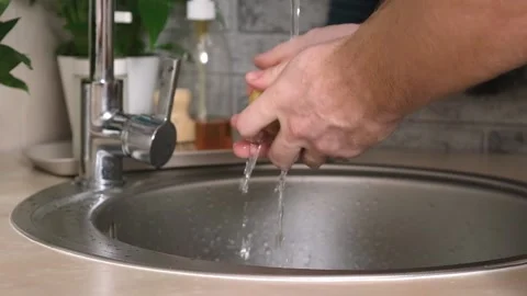A man washes a potato from ground under a stream of tap water for further Stock Footage 231518081