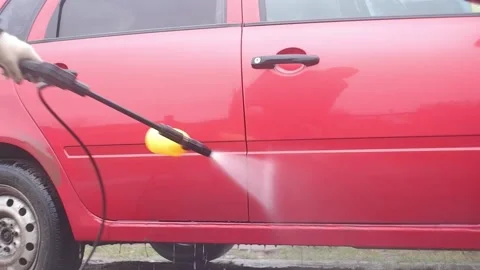 A man washes a red car with a high-pressure washer Stock Footage 165127480