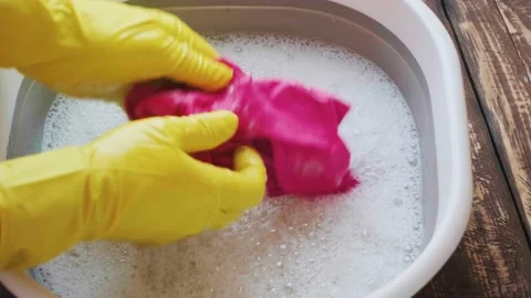 A man washes a red cloth in a basin Stock Footage 232655499