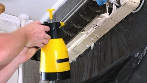A man washes off special foam for cleaning air conditioners with a jet of water Stock Footage 201384566