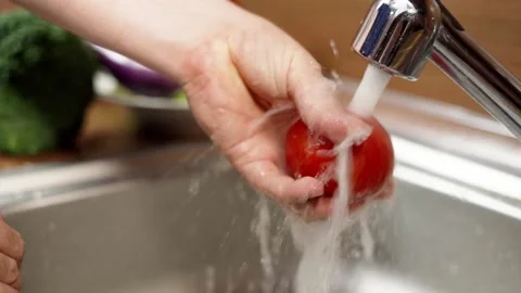 A man washes an tomato under running water from a tap. Stock Footage 160616022