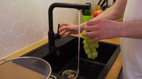 A man washes under running water grapes Stock Footage 129054486