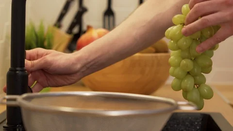 A man washes under running water grapes Stock Footage 129054510