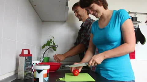 Man washes vegetables in the kitchen, and a woman cuts it for salad Video stock 39840130