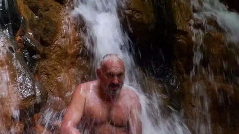 A man washes in a waterfall. Video stock 122271662