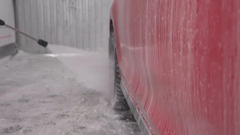 A man washes the wheels of a red car, close-up Stock Footage 104876250