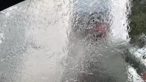 Man washes windshield of automobile with pressurized jet. Blurred glass with Stock Footage 274048334