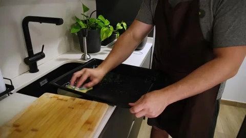 Man washing baking tray in a modern kitchen sink Stock Footage 345733435